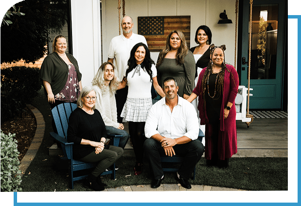 A group of people sitting on chairs in front of a house.